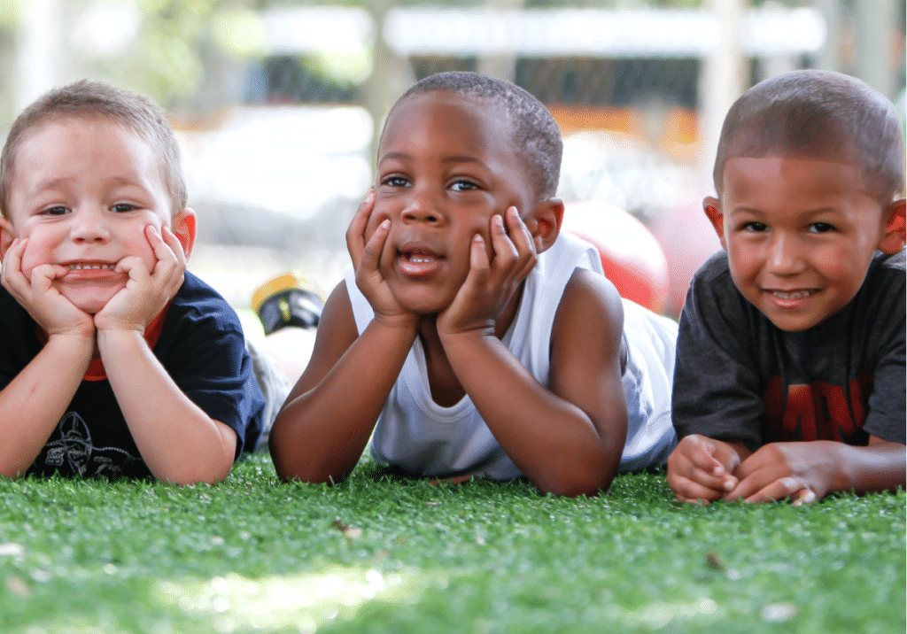 three smiling boys laying in the grass